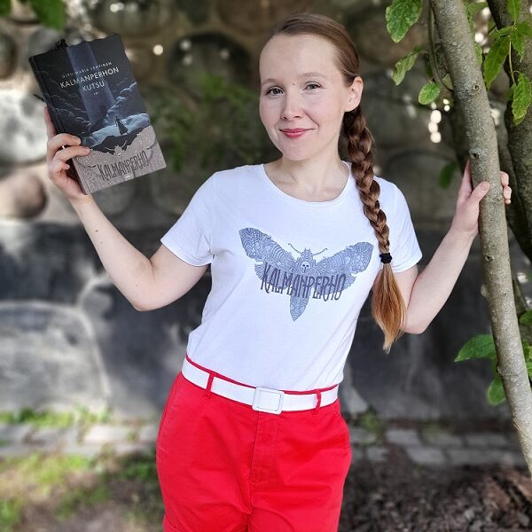 Kirjailija Ulpu-Maria Lehtinen esittelee kirjaansa. Hänellä on päällään valkoinen t-paita, jossa sama perhoskuva kuin kirjan kannessa ja teksti Kalmanperho.